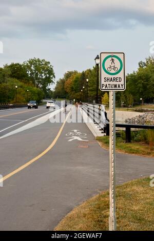 Ottawa, Ontario, Kanada - 20. August 2021: Fußgänger und Radfahrer fahren auf einem Pfad entlang der Hog's Back Road hinter einem 'Shared Pathway'-Schild. Stockfoto