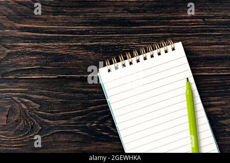 Vorlage für Text und Design. Leerer weißer Notizblock und ein Marker auf altem dunklen Holzhintergrund Stockfoto