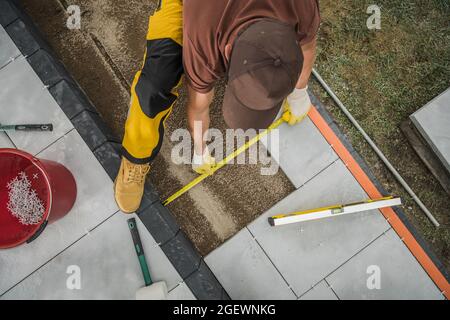 Kaukasische kleine Architektur Arbeiter Pflasterung Wohn Patio-Bereich, indem im Freien Betonfliesen. Industriedesign. Stockfoto