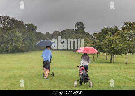 Kenmare, Kerry, Irland. August 2021. Vater und Sohn, Patrick und Darragh Crushell trotzen den Elementen und machen sich ihren Weg auf den Fairway, während ein sintflutartiger Regen während ihres Golfspiels in Kenmare, Co. Kerry, Irland, fällt. - Bild; David Creedon- Bild; David Creedon / Alamy Live News Stockfoto