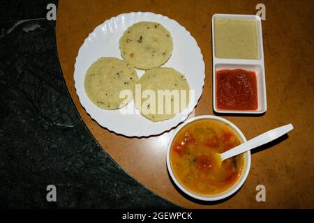 Beliebtes südindisches Frühstück Rava idli mit hausgemachtem Sambar und zwei Arten von Chutney, weißem Chutney und Rot auf dem Tisch serviert Stockfoto