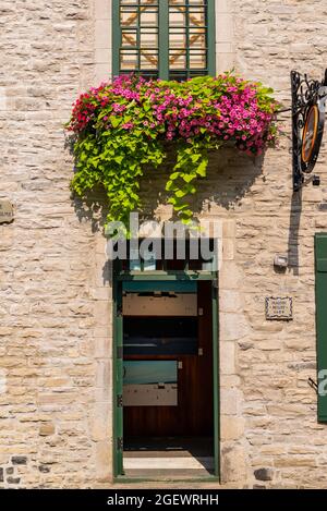 Quebec, Kanada - Juli 21 2021: Fassade eines gemauerten Hauses mit Bakonen, die mit wunderschönen Blumen geschmückt sind, in der Innenstadt von Quebce City Stockfoto