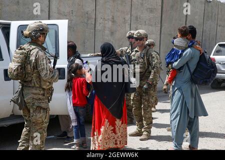 US-Soldaten der 3. Brigade, 10. Bergdivision, begleiten Evakuierte zum Terminal, um während einer Evakuierung am Hamid Karzai International Airport, Kabul, Afghanistan, am 20. August einzuchecken. US-Dienstmitglieder unterstützen das Außenministerium bei einer geordneten Abseichung von designiertem Personal in Afghanistan. (USA Marine Corps Foto von Lance CPL. Nichola Guevara) Stockfoto