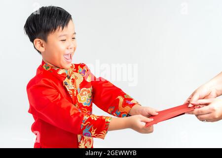 Asiatischer vietnamesischer Junge, der auf dem Mond-Neujahrsfest rote Papiertüten oder Geld von einem anderen erhält, wobei das traditionelle Ao dai auf weißem Hintergrund isoliert ist Stockfoto