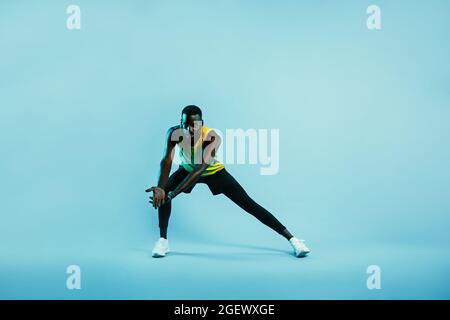 Männlicher Athlet macht Stretching-Übungen. Junger Mann in Sportkleidung, der Beine und Arme aufwärmt. Stockfoto