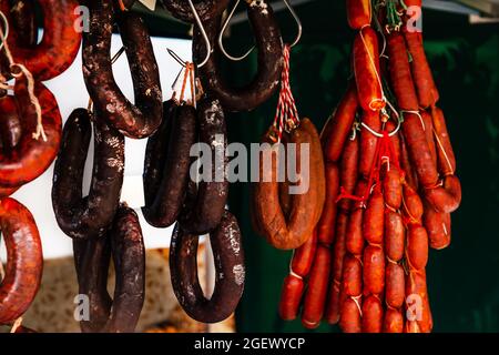 Typische spanische Würste hängen an einem Dorfstand am Lebensmittelmarkt, traditionelle Fleischprodukte Stockfoto