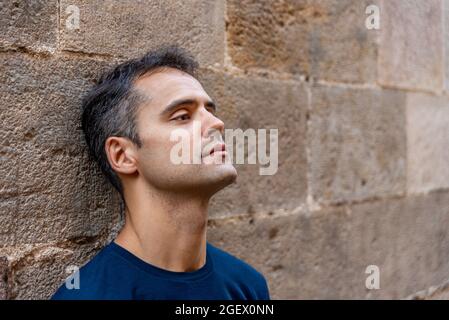 Junger mann aus latein, der im Freien gegen eine Mauer steht Stockfoto