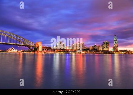 Farbenfroher Sonnenuntergang über der Skyline von Sydney CBD über dem Hafen von Sydney - die Felsen, die Hafenbrücke, Barangaroo - hell erleuchtet. Stockfoto