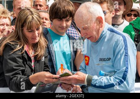 John Surtees signiert Autogramme beim Goodwood Festival of Speed. Legendärer Formel-1-Grand-Prix-Rennfahrer. Veteran Rennfahrer in Rennen Overalls Stockfoto