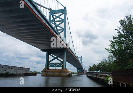 Die Benjamin Franklin Bridge überspannt den Delaware River an einem bewölkten Tag und wird vom Pier der Race Street in Philadelphia, Pennsylvania, aus gesehen -03 Stockfoto