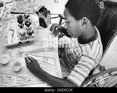 Austin Texas USA, 1984: Patrick Skeaton, ein behinderter Junge im Rollstuhl, zeichnet sich während der Kunstklasse in der Grundschule mit einem Bein. ©Bob Daemmrich Stockfoto