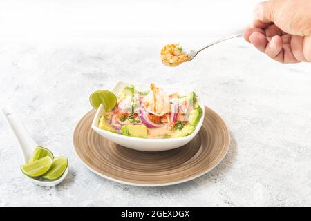 Hand nehmen eine Garnele von einem Ceviche-Teller Stockfoto