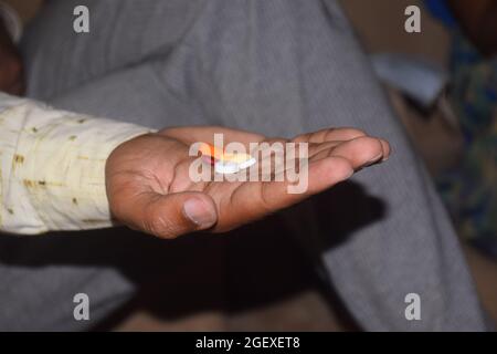 Nahaufnahme der Hand eines jungen Mannes mit Pillen und einem Glas Wasser, er wird etwas Medizin nehmen Stockfoto