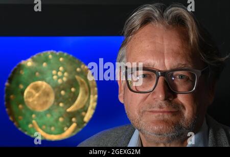 17. August 2021, Sachsen-Anhalt, Halle (Saale): Harald Meller, Landesarchäologe und Honorarprofessor am Institut für Europäische Archäologie der Martin-Luther-Universität Halle-Wittenberg, steht neben der Himmelsscheibe von Nebra im Landesmuseum. Als der Archäologe Meller im März 2001 seine Arbeit am Landesmuseum Halle begann, war die Einrichtung bereits seit Jahren geschlossen. Weniger als ein Jahr später, im Februar 2002, wurde die Himmelsscheibe von Nebra mit Hilfe von Meller in einem Hotel in Basel, Schweiz, gerettet. Zwanzig Jahre später gilt das Museum in Halle als Zentrum der Regionalarchäologie in Deutschland Stockfoto