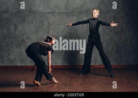 Tänzer in schwarzen Kostümen tanzen im Tanzsaal Rumba Stockfoto