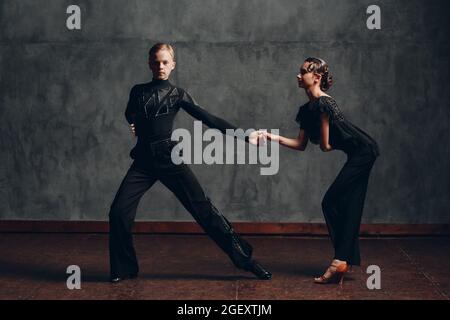 Paar junge Mann und Frau in schwarzem Kleid tanzen in Ballsaal Tanz Rumba Stockfoto