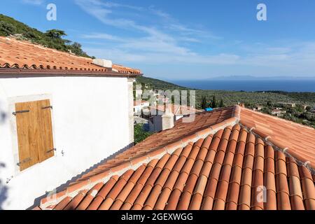 Blick auf das Dorf Vuno - traditionelle weiße Häuser mit orangefarbenen Dächern und hölzernen Fensterläden, auf dem Berg, Südalbanien Stockfoto
