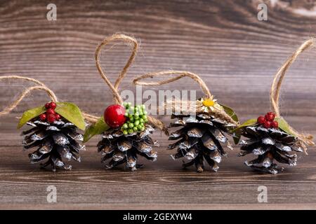 Handgemachtes Weihnachtsbaumspielzeug aus Kiefernzapfen, verziert mit natürlichen Materialien, vor dem Hintergrund eines geschnittenen Baumes. Dekorationen mit Hanf-Suspension Stockfoto