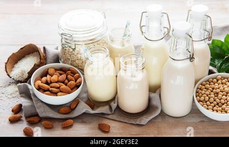 Alternative Arten von veganen Milchsorten in Glasflaschen auf betontem Hintergrund. Draufsicht Stockfoto