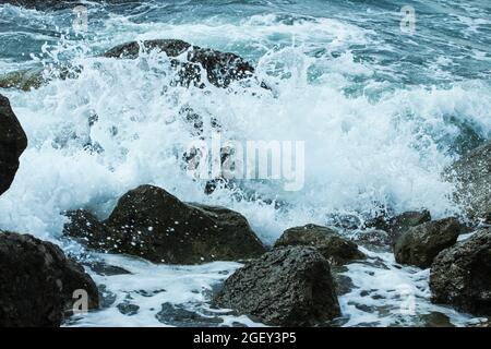 Meereswellen stürzen gegen Felsen und sprühen Stockfoto