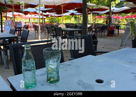 Leeres Glas Coca-Cola Flasche und leeres Glas mit Eis und Zitrone auf einem Tisch leeres Barcafé Terrasse El Retiro Park Madrid Spanien Stockfoto