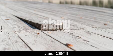 Nahaufnahme eines Holzbodens mit einem hervorragendem Brett. Stockfoto