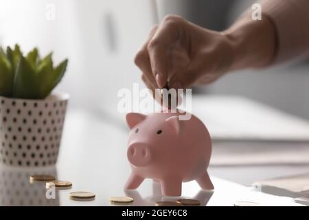 Nahaufnahme weibliche Finger legen Münze in rosa Sparschwein Stockfoto