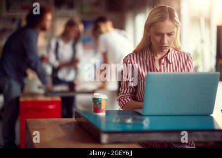 Schöne junge kaukasische weibliche Blondine, die im Freiraumbüro an ihrem Laptop arbeitet und besorgt aussieht Stockfoto