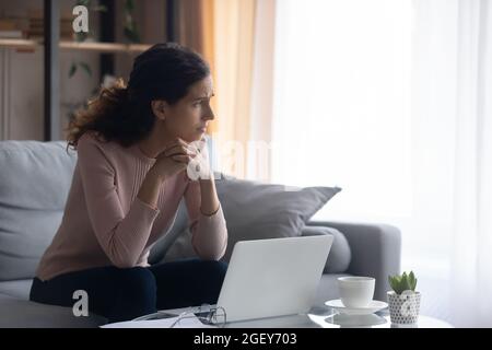 Traurige Frau sieht traurig über schlechte Nachrichten online beiseite Stockfoto