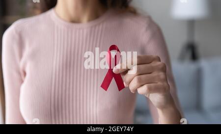 Nahaufnahme einer Freiwilligen-Frau, die das rote Band in den Händen hält Stockfoto