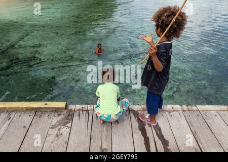 Friwin, Indonesien - 14. Okt 2019: Kinder spielen und versuchen, etwas von einem hölzernen Steg, Raja Ampat, West Papua, zu fischen Stockfoto