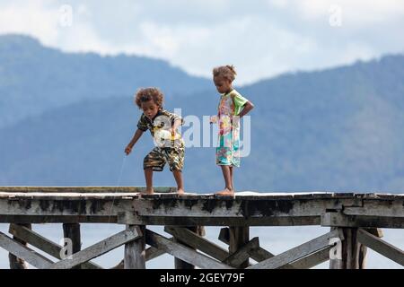 Friwin, Indonesien - 14. Okt 2019: Kinder spielen und versuchen, etwas von einem hölzernen Steg, Raja Ampat, West Papua, zu fischen Stockfoto