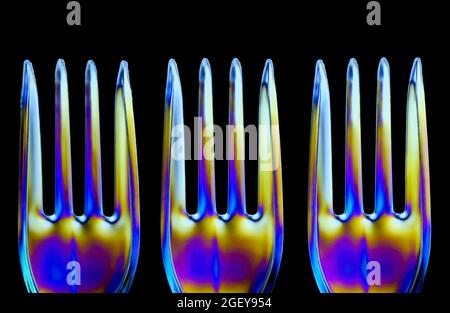 Auf durchsichtigen Kunststoffgabeln bilden sich farbenfrohe Muster, die durch die Brechung polarisierten Lichts verursacht werden Stockfoto