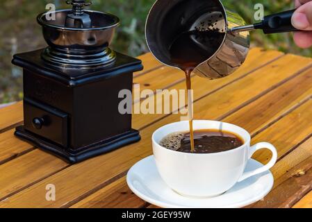 Frischer Kaffee aus einer in die Tasse gegossene Cizve Stockfoto