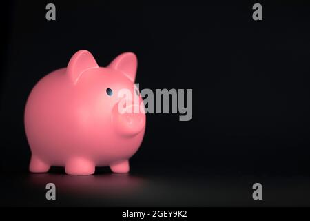 Pink Piggy Bank horizontal auf schwarzem Hintergrund mit Kopierraum, Business-, Sparungs- und Finanzkonzept Stockfoto