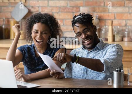 Glücklich aufgeregt junge Schwarze Paar feiert finanziellen Erfolg Stockfoto