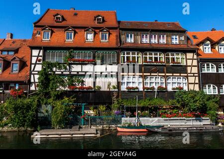Malerischer Blick auf die mittelalterlichen Gebäude entlang der Regnitz mit alten Lastkahn, festfahrenden Booten und am Ufer, Bamberg Deutschland Stockfoto