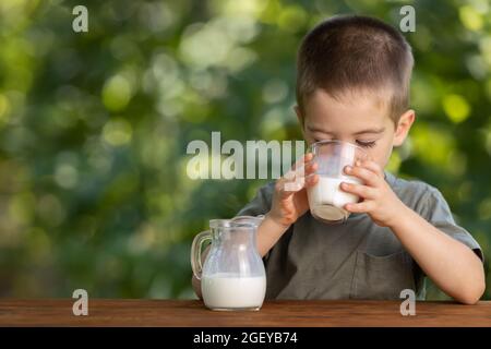 Kleiner Junge, der im Freien Milch aus Glas trinkt Stockfoto