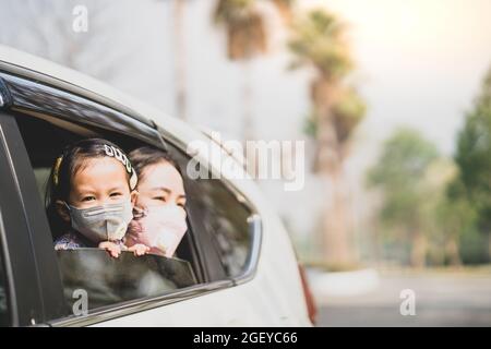 Die Mutter und ihre Tochter tragen medizinische Schutzmasken und sitzen im Auto Stockfoto