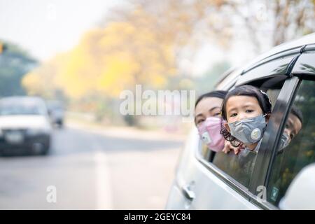Die Mutter und ihre Tochter tragen medizinische Schutzmasken und sitzen im Auto Stockfoto