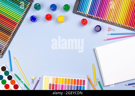 Kreative Kunstwerke liefern Hintergrund. Aquarell, Pinsel, Bleistifte, Notizbuch auf hellgrauem Tisch. Draufsicht, flach liegend Stockfoto