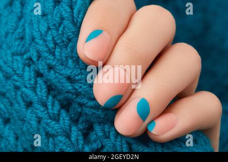 Nahaufnahme der Womans Hand mit Sommer-Maniküre auf Strickmaterial. Trends im Maniküre-Design Stockfoto