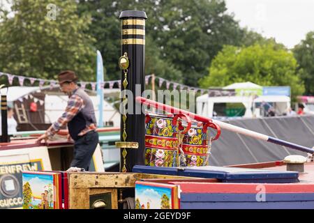 Crick, Northamptonshire, Großbritannien, 22. August 2021: Traditionell bemalte Krüge an einem mit Messing gebundenen Kamin auf dem Dach eines Schmalbootes auf der Crick Boatshow. Stockfoto