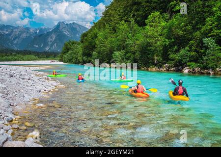 Majestätischer Rafting- und Kajakplatz auf dem Fluss. Aktive Kajakfahrer in farbenfroher Schwimmweste paddeln und trainieren auf dem türkisfarbenen Soca River, B Stockfoto