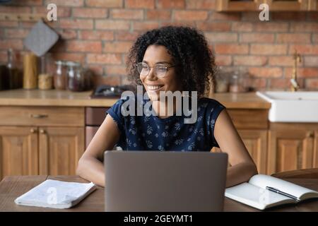 Fröhlicher afroamerikanischer Fernprofi in einer Brille, die am Laptop arbeitet Stockfoto