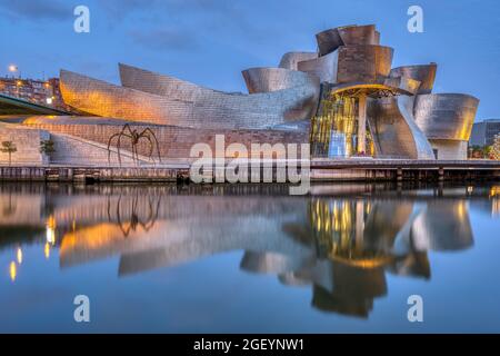 BILBAO, SPANIEN - 10. Juli 2021: Das berühmte Guggenheim Museum spiegelt sich im Morgengrauen im Fluss Nervion wider Stockfoto