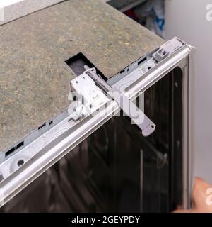 Reparieren eines Hausspülers. Der Master zieht den eingebauten Geschirrspüler zur Reparatur heraus Stockfoto