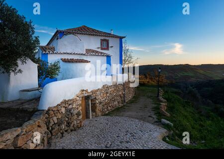 Blick auf ein traditionelles Haus in weiß und blau, mit landwirtschaftlichen Feldern im Hintergrund, in der Nähe von Mafra, Portugal. Stockfoto