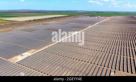Drohnenansicht eines riesigen Solarenergieparks mit landwirtschaftlichen Feldern im ländlichen Hintergrund. Stockfoto