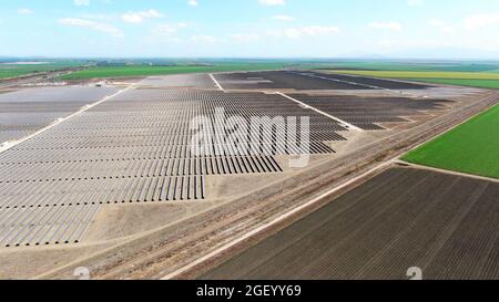 Drohnenansicht eines riesigen Solarenergieparks mit gepflügten landwirtschaftlichen Feldern auf dem Land. Stockfoto